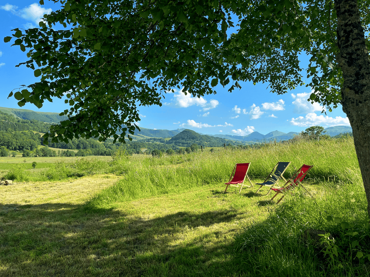 Trois chaises longues face à un paysage vallonné.